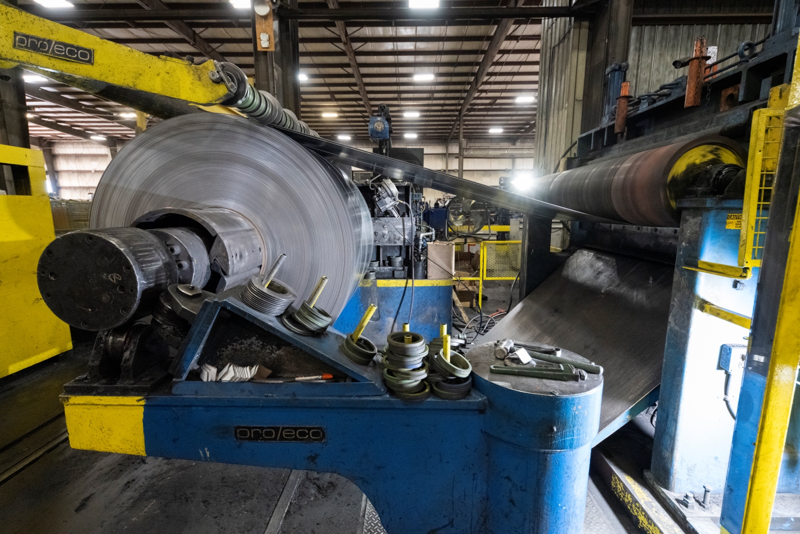 Hot Rolled Steel Coil Processing Hot rolled steel coil being processed on industrial machinery with tools and equipment visible in the foreground.