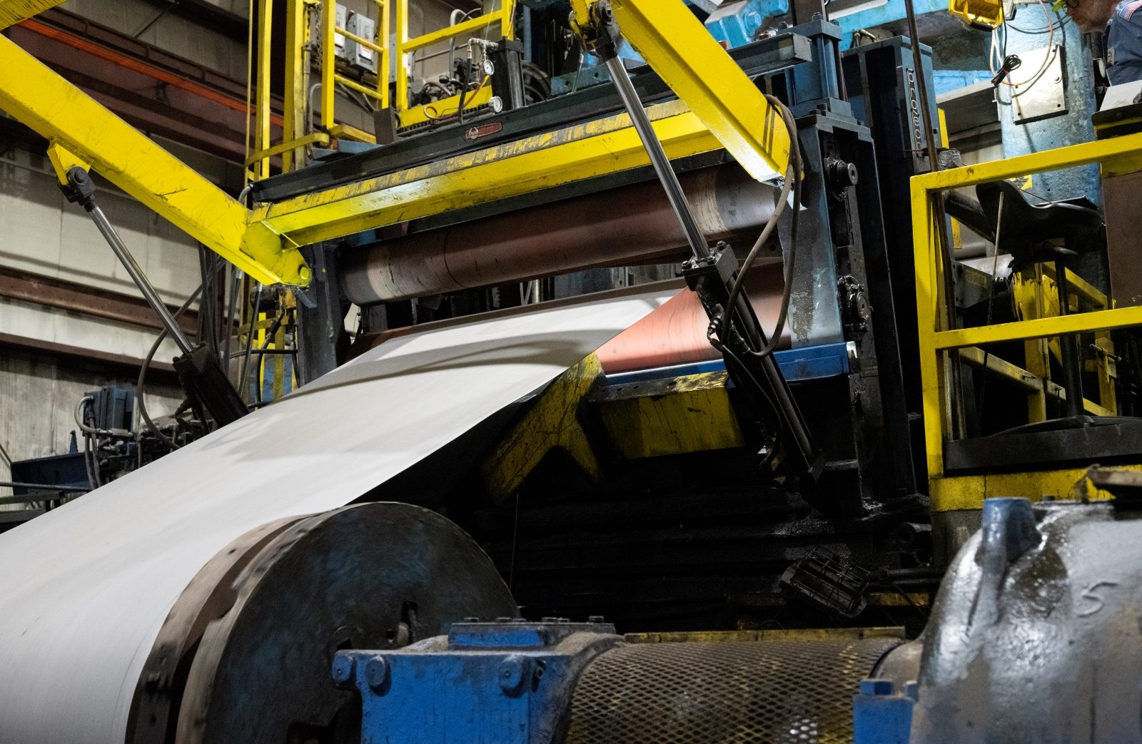 Tempering Process for Steel Sheets Steel sheet undergoing the tempering process on industrial machinery with yellow structural supports visible.