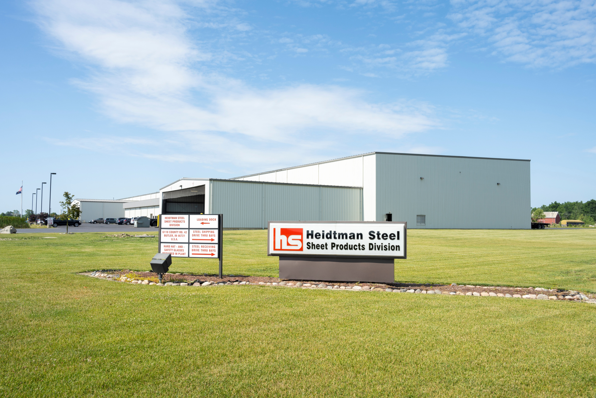 Heidtman Steel Butler, Indiana Sheet Division Exterior view of Heidtman Steel’s Butler, Indiana Sheet Products Division, featuring a large white industrial facility with company signage and a well-maintained landscape.