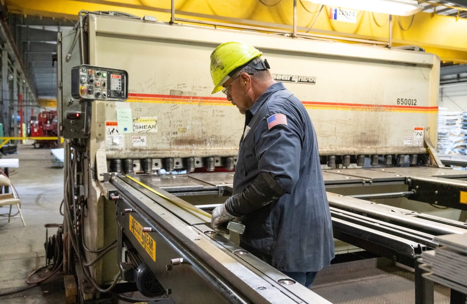 Shearing Process at Heidtman Steel Worker in a hard hat operating a shearing machine in an industrial facility.