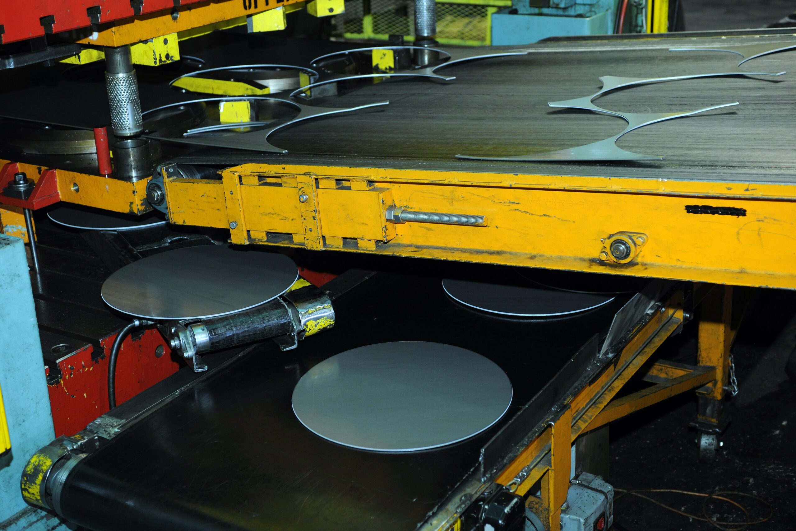 Blanking Process for Metal Discs Blanking process machine cutting metal discs on a conveyor in a factory.